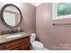Powder room with granite countertop, wood vanity and round mirror at 9009 Tayside Ct, Huntersville, NC 28078