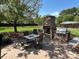 Outdoor brick patio with a stone fireplace and grill, surrounded by a green lawn and mature trees at 901 Ridge St, Albemarle, NC 28001