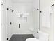 Modern white tile shower with black fixtures, glass doors, a built in seat and a black honeycomb floor at 9020 Tynecastle Commons Ct, Charlotte, NC 28226