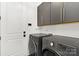Modern laundry room with gray cabinets, a white door, and a new LG washer and dryer at 9020 Tynecastle Commons Ct, Charlotte, NC 28226