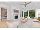 Bright living room with a white fireplace, modern ceiling fan, hardwood floors, and large windows with greenery views at 9020 Tynecastle Commons Ct, Charlotte, NC 28226