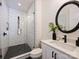 Modern bathroom with black hardware, tiled shower, shiplap wall, and round decorative mirror at 100 Verbena Ct, Weddington, NC 28173