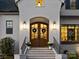 Elegant front entrance featuring a beautiful wood door, white brick, and stylish sconces at 100 Verbena Ct, Weddington, NC 28173