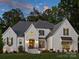 Stunning white brick home with manicured lawn, tasteful landscaping, and elegant architectural details at dusk at 100 Verbena Ct, Weddington, NC 28173