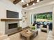 Bright living room features a fireplace, wood beams, modern lighting, and an open flow to an outdoor living space at 100 Verbena Ct, Weddington, NC 28173