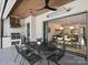 Outdoor kitchen and dining area with stainless steel grill, ceiling fan, and view into the dining room at 100 Verbena Ct, Weddington, NC 28173