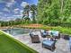 Luxurious outdoor space featuring a modern pool, stone patio, and comfortable seating area at 100 Verbena Ct, Weddington, NC 28173