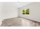 Well-lit bedroom with a large window offering lush greenery views and wood-look floors at 1301 Marble St, Charlotte, NC 28208