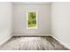 The simple bedroom includes laminate floors and a window with a view of trees and greenery at 1301 Marble St, Charlotte, NC 28208