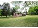 Expansive backyard featuring a brick home, wooden deck and steps surrounded by lush greenery and mature trees at 134 Piedmont Dr, Kannapolis, NC 28081