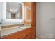 A bathroom features a granite countertop, wooden cabinetry, and a brightly lit mirror at 1592 Farmington Hills Dr, Conover, NC 28613
