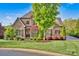 Beautiful home featuring a blend of stone and brick, accented by lush greenery and mature trees at 17909 Golden Meadow Ct, Davidson, NC 28036