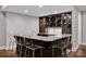 Wet bar with marble countertop and transparent barstools next to dark wood cabinets at 17909 Golden Meadow Ct, Davidson, NC 28036