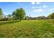 Large, grassy backyard with mature trees and home in distance, partially fenced and private at 1821 Hopewell Church Rd, Hiddenite, NC 28636