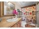 Cozy bathroom featuring a tiled vanity, decorative mirror, and shower with a patterned curtain at 1821 Hopewell Church Rd, Hiddenite, NC 28636