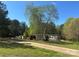 Exterior view of a single-wide home and garage on a dirt road with trees surrounding the property at 1869 Wooten St, Catawba, NC 28673
