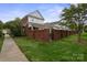 Beautiful exterior view of a white and brick home, complemented by manicured lawns and a wrought iron gate at 20217 Middletown Rd, Cornelius, NC 28031