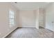 Spacious bedroom with neutral paint, trim accents, a large window with grid pattern, and modern gray vinyl flooring at 2515 Carya Pond Ln, Charlotte, NC 28212