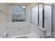 Bright bathroom featuring a soaking tub under a window and a glass-enclosed shower at 2684 Sunberry Nw Ln, Concord, NC 28027