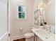 Updated powder room featuring a pedestal sink, window, and a decorative mirror at 3064 Selwyn Ave, Charlotte, NC 28209
