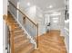 Carpeted staircase with wooden banister leading to a hallway with hardwood floors at 3129 Burnello Ct, Iron Station, NC 28080