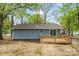 Rear view of blue home featuring wooden deck and sliding glass doors surrounded by lush, mature trees at 313 Villa St, Kannapolis, NC 28083