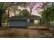 Rear view of blue home featuring wooden deck and sliding glass doors surrounded by lush, mature trees at 313 Villa St, Kannapolis, NC 28083
