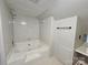The white tiled bathroom offers a bathtub and shower with a small sink area to the side at 3824 Freedom Dr, Charlotte, NC 28208