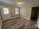 Bright living room features wood-look flooring, neutral paint, a window, and a white door with glass panels at 3824 Freedom Dr, Charlotte, NC 28208