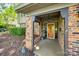 Inviting front porch with brick columns, cozy decor, and a vibrant orange front door with sidelights at 4224 Firwood Ln, Charlotte, NC 28209