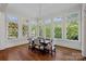 Light-filled dining room boasts large windows with diamond panes, hardwood floors, and a modern chandelier at 503 Walnut St, Davidson, NC 28036