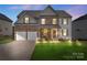 Charming two-story home featuring a stone facade, covered porch, and well-manicured lawn at 5035 Terrier Ln, Fort Mill, SC 29707
