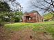 View of the backyard showing the brick home, a wooded area, and a wood deck at 6316 Glengarrie Ln, Huntersville, NC 28078