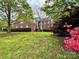 Brick home surrounded by lush greenery, including flowering shrubs and mature trees at 6316 Glengarrie Ln, Huntersville, NC 28078