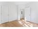 A bright bedroom with hardwood flooring has two doors and a hallway in view at 656 Garden District Dr, Charlotte, NC 28202