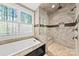 Bright bathroom featuring a soaking tub, window, and a luxurious glass enclosed walk-in shower at 7181 Windy Ridge Dr, Iron Station, NC 28080