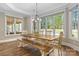 Bright dining area with a large wooden table, bench seating, and big windows showcasing a green lawn at 7181 Windy Ridge Dr, Iron Station, NC 28080