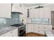 Stainless steel stove top and granite countertop with tile backsplash and white cabinets at 7181 Windy Ridge Dr, Iron Station, NC 28080