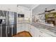 Granite countertop, stainless steel refrigerator and microwave with site lines into the living room at 7181 Windy Ridge Dr, Iron Station, NC 28080