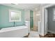Well-lit bathroom featuring a modern soaking tub and glass-enclosed shower with green accent tiles at 7200 Monroe Rd, Charlotte, NC 28212