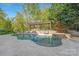 Scenic pool surrounded by lush greenery, featuring a stone patio, pergola, and comfortable lounge seating at 7311 Barrington Ridge Dr, Fort Mill, SC 29707