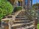 Elegant stone stairway with metal railings leading to the home's entrance, enhanced by lush greenery at 7311 Barrington Ridge Dr, Fort Mill, SC 29707