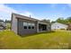 View of the home's backyard and covered patio with large lawn and gray siding and a line of windows at 8018 Green Heron Ct, Belmont, NC 28012