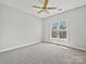 A bedroom featuring neutral walls, carpet, a ceiling fan and a bright window at 8274 Windsor Ridge Dr, Charlotte, NC 28277