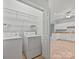 A laundry room equipped with a washer, dryer, shelving and an open doorway to another room at 8274 Windsor Ridge Dr, Charlotte, NC 28277