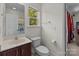 Well-lit bathroom featuring a vanity, mirror, toilet, and a window overlooking the backyard at 9494 Leyton Dr, Harrisburg, NC 28075