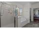 Bathroom featuring a glass shower, soaking tub under a window and access to a commode at 9494 Leyton Dr, Harrisburg, NC 28075