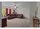 Spacious living room featuring a plush sectional sofa, ceiling fan, and large windows with red curtains at 9494 Leyton Dr, Harrisburg, NC 28075