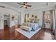 Well-lit primary bedroom featuring a ceiling fan, hardwood floors, and three large windows at 9494 Leyton Dr, Harrisburg, NC 28075