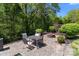 Outdoor patio featuring stone pavers, a dining set, fire pit, and lush landscaping at 9494 Leyton Dr, Harrisburg, NC 28075